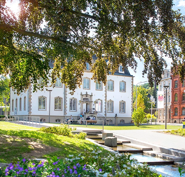 Fritz K&uuml;hn Platz in Iserlohn, wei&szlig;es Geb&auml;ude umgeben von Gr&uuml;n